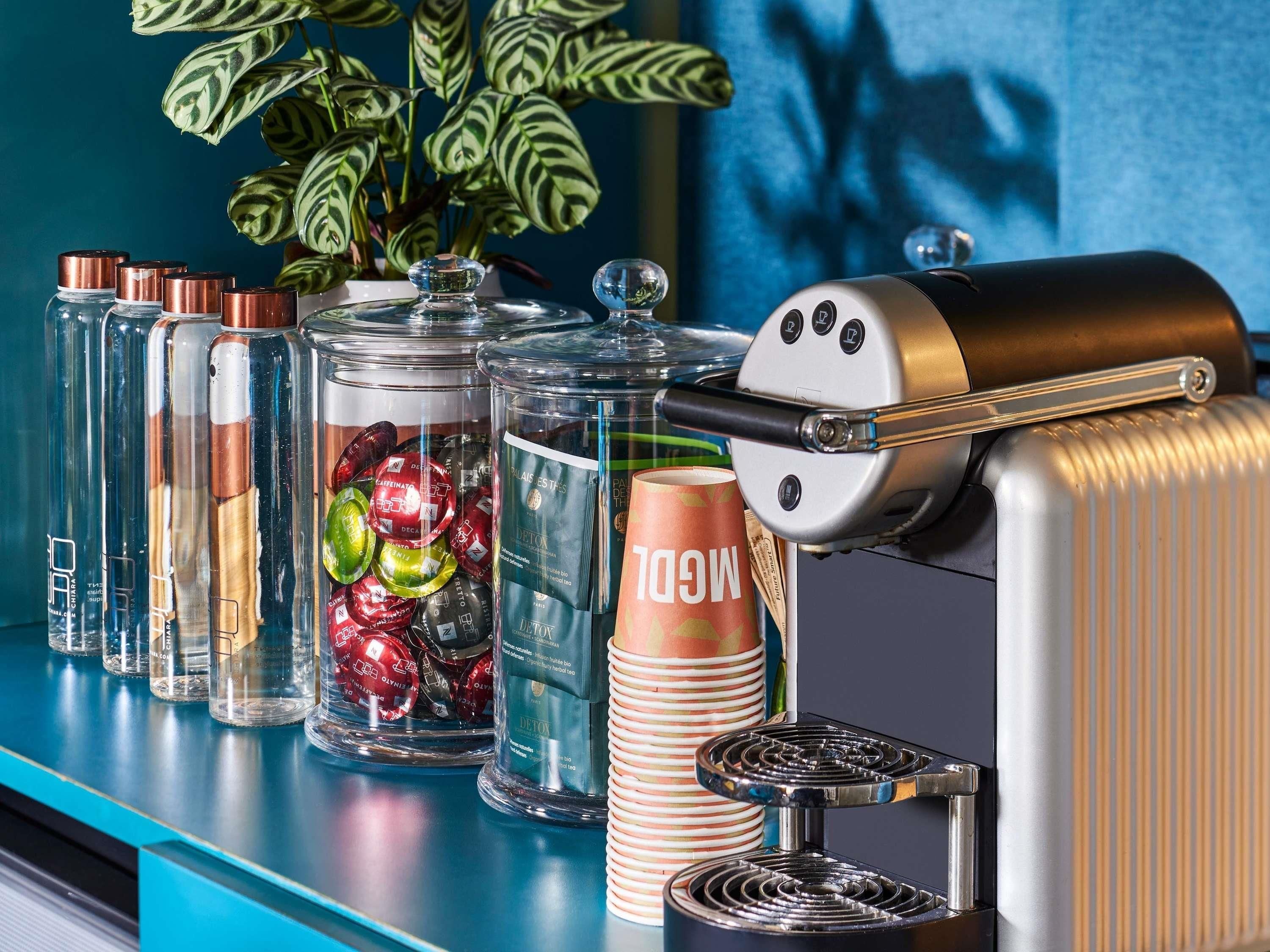 Angolo bar con macchina per caffè, contenitori di vetro con snack e una pianta.