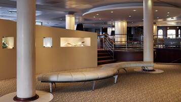 A modern lobby with a curved bench, large columns, and a staircase.