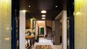 A modern interior with a staircase, a wooden table with potted plants, and a patterned rug. - Le Stendhal - Vendôme (Paris)