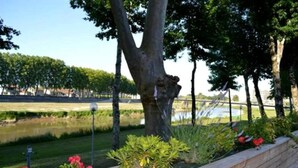 A landscaped area with a pond, trees, and a wooden bench. - Dax Hôtel (Dax)