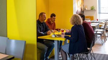 A group of people seated around a yellow table in a brightly lit room with a modern design.