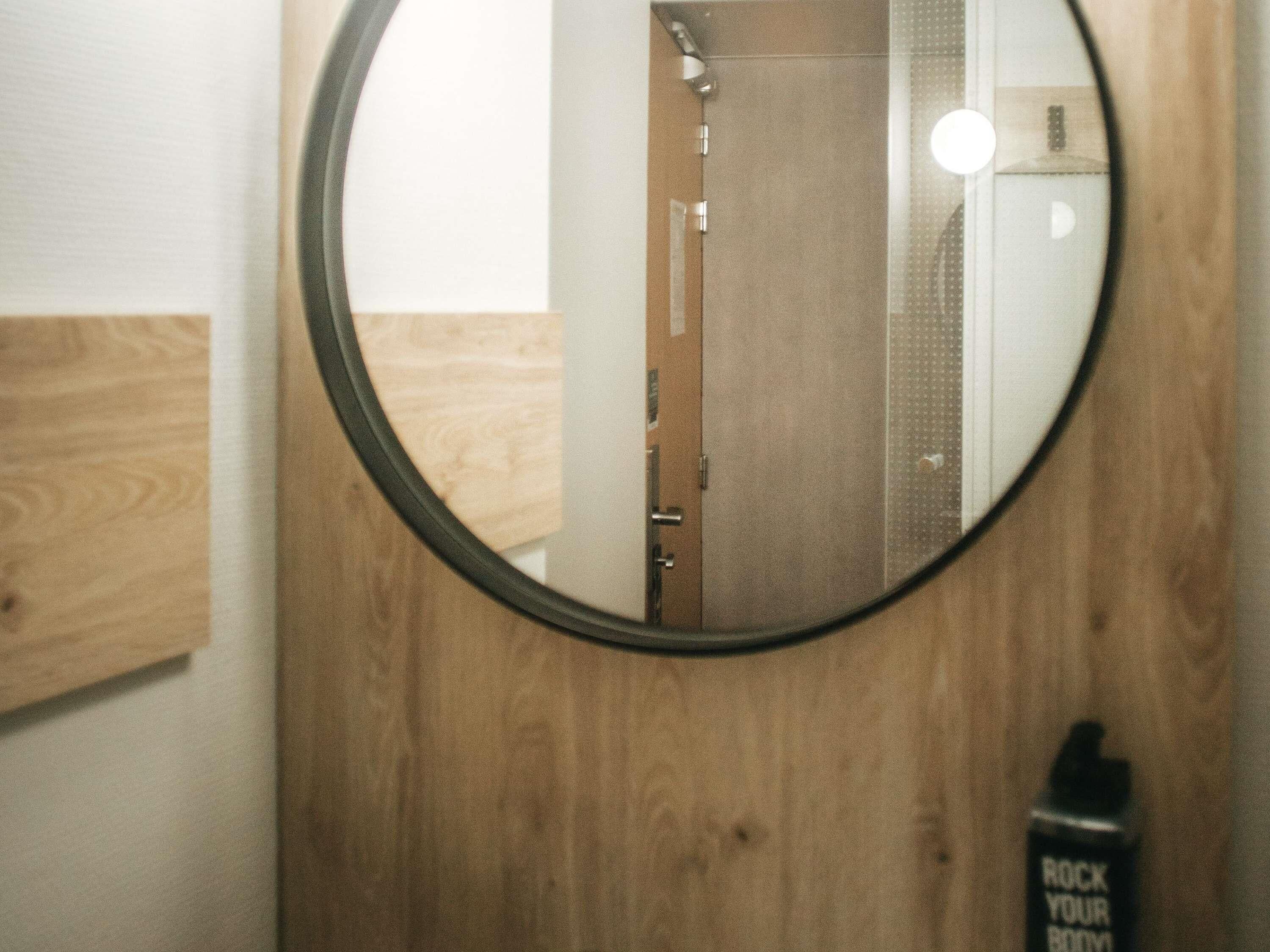 A bathroom with a wooden vanity, a mirror, and a bottle of hand soap.