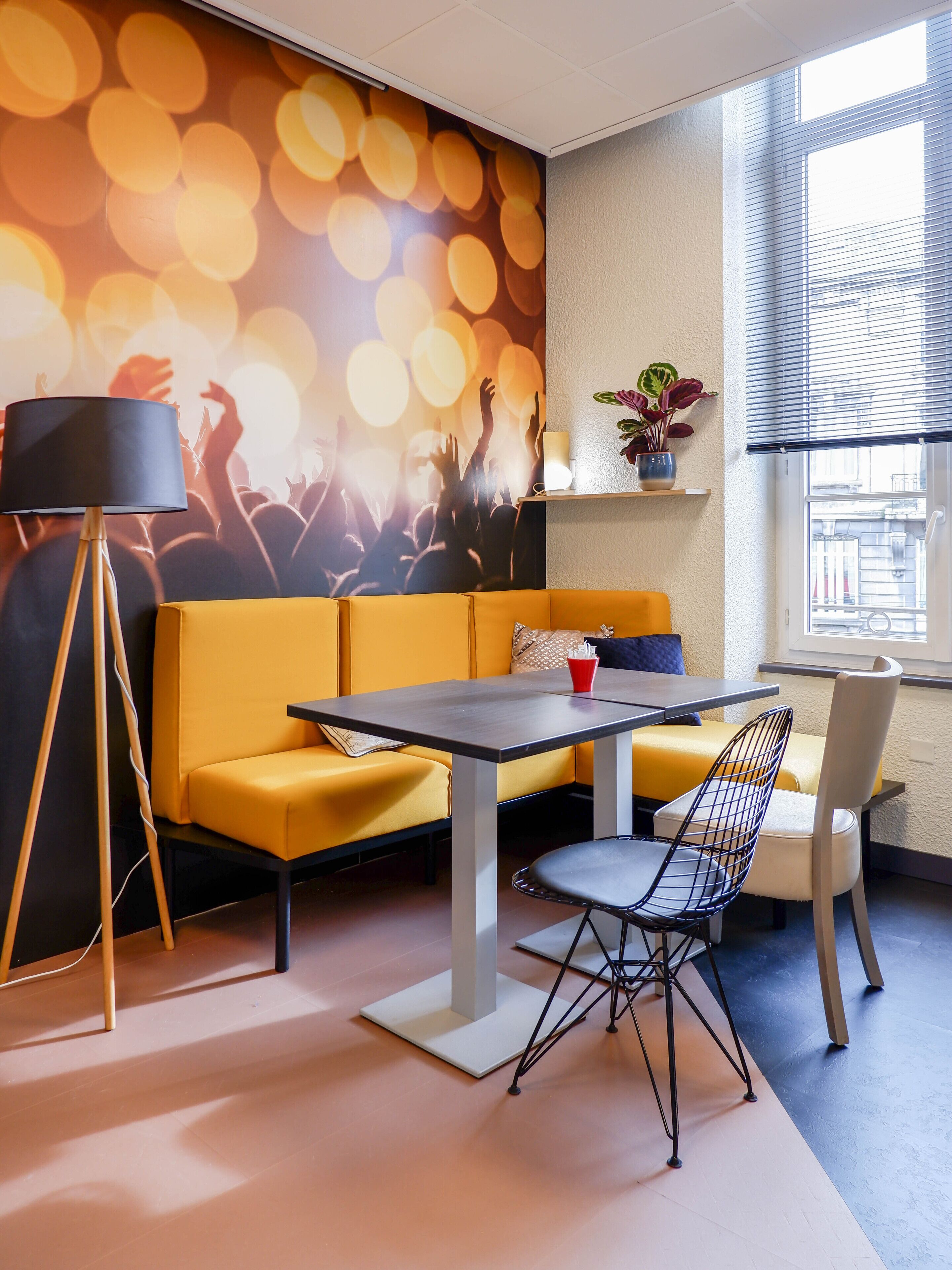 Een moderne zithoek met een bank, een tafel en stoelen, met een levendige oranje wand en een bokeh-lichteffect.