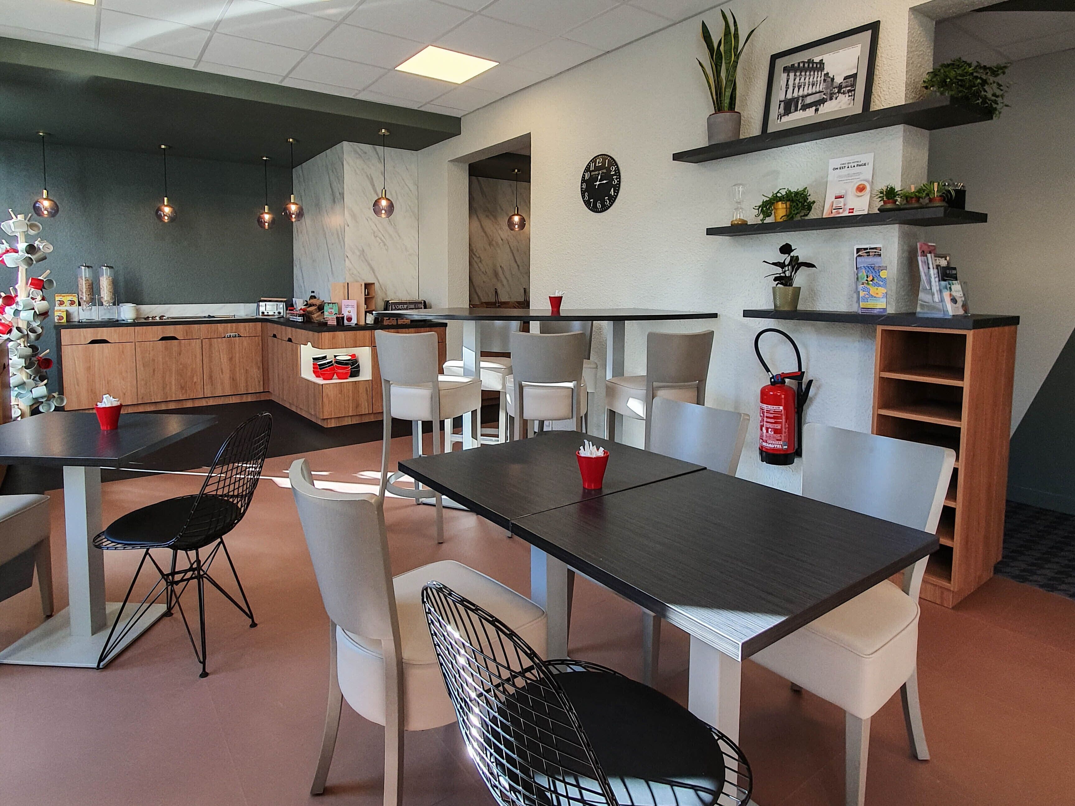 Un espace repas moderne avec une table noire, des chaises blanches et une cuisine en arrière-plan.
