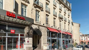 Et hotel med et tydeligt 'ibis Hotel' skilt, store vinduer og en rød markise.