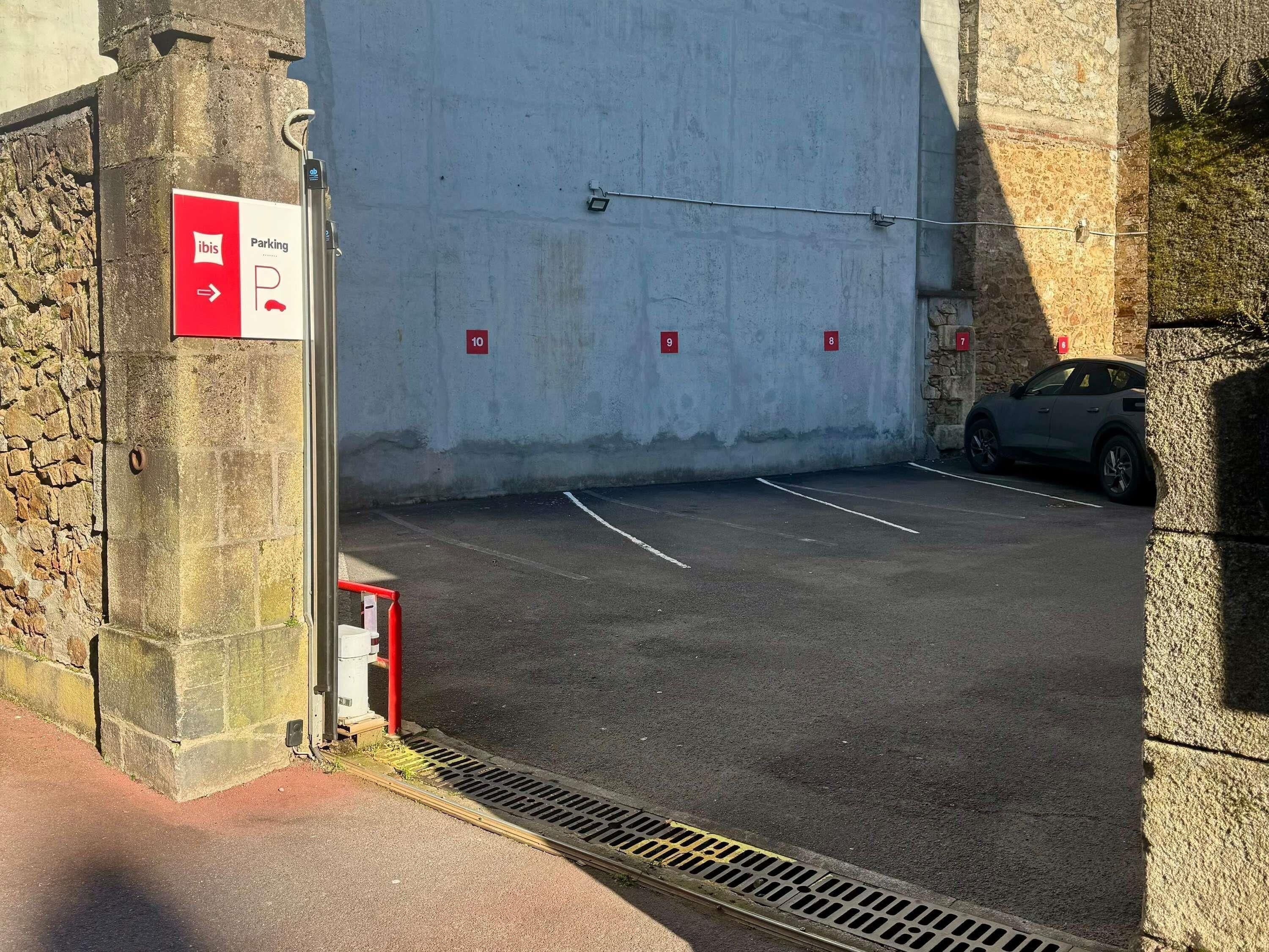 Een parkeerplaats met genummerde plekken en een bord dat de richting naar de parkeerplaats aangeeft.