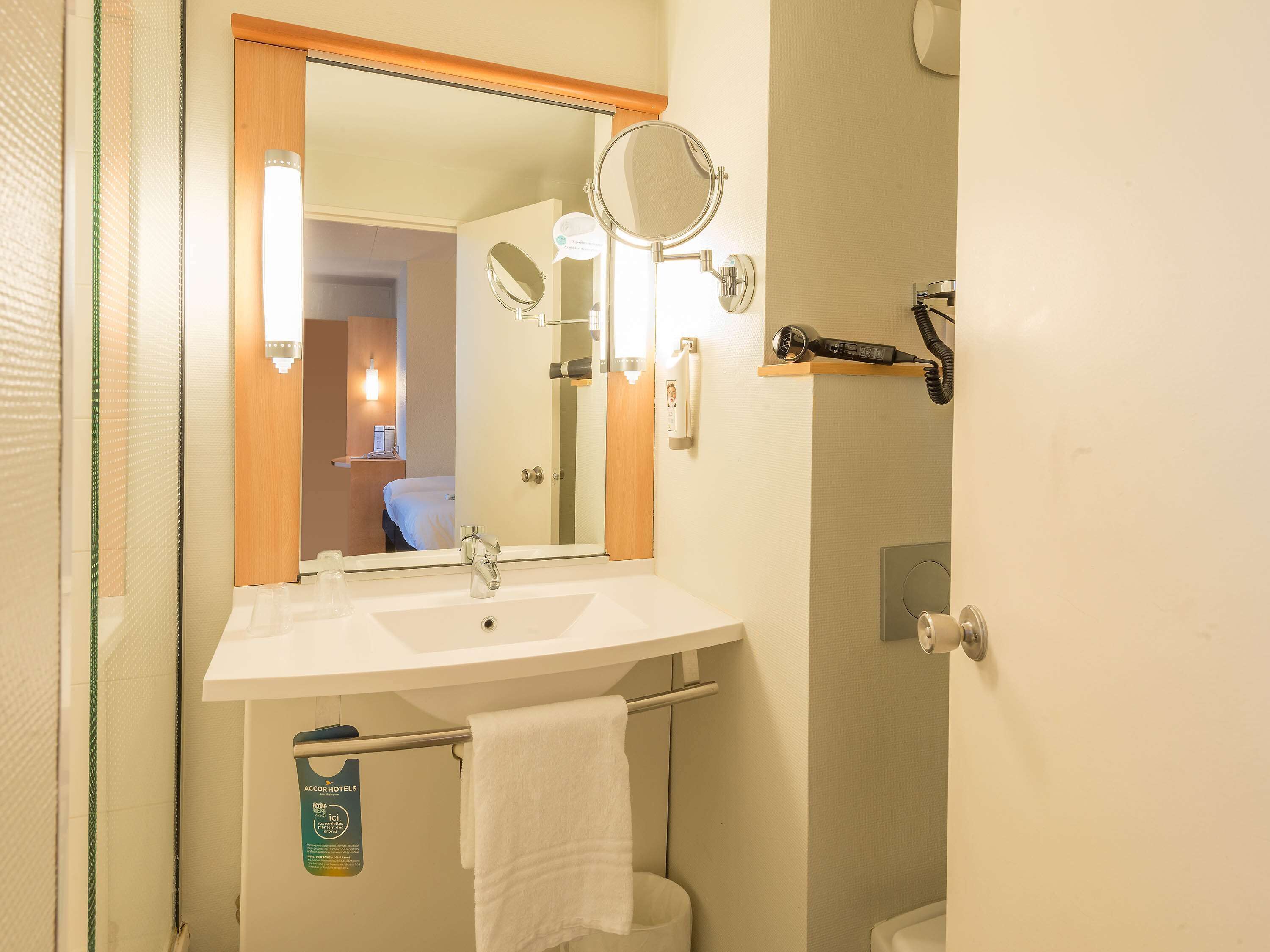 A bathroom with a sink, mirror, towel rack, and a hairdryer on a shelf.