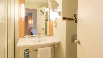 A bathroom with a sink, mirror, towel rack, and a hairdryer on a shelf.