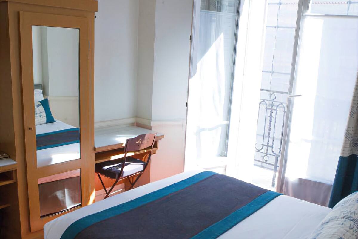 Ein Hotelzimmer mit Bett, Schreibtisch, Stuhl, Kleiderschrank und einem Fenster mit Blick.