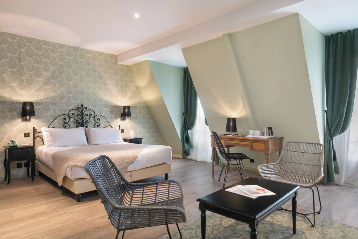 Un dormitorio con una cama, dos sillones, un escritorio y una mesita de noche.