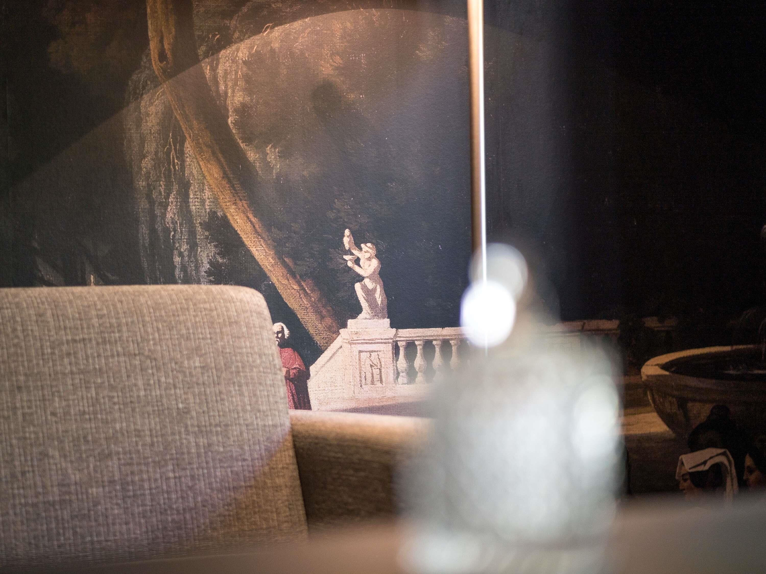 Une pièce comprenant un grand tableau, un canapé et une petite statue.