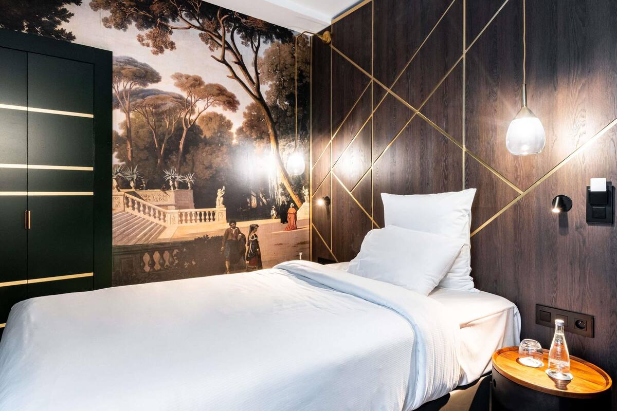 Quarto moderno com cama grande, um mural de uma paisagem de parque e uma parede de madeira com padrões geométricos.