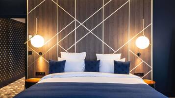 Una habitación de hotel moderna con una cama grande, dos mesitas de noche y un cabecero con estampado geométrico.