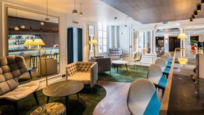 Un hall d’hôtel comprenant des espaces de détente, un bar et un comptoir d’accueil.