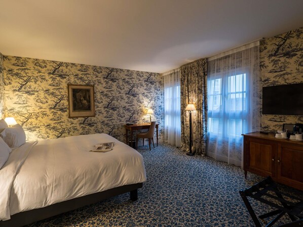 Una habitación de hotel con una cama, un escritorio, una silla, una lámpara y un televisor.