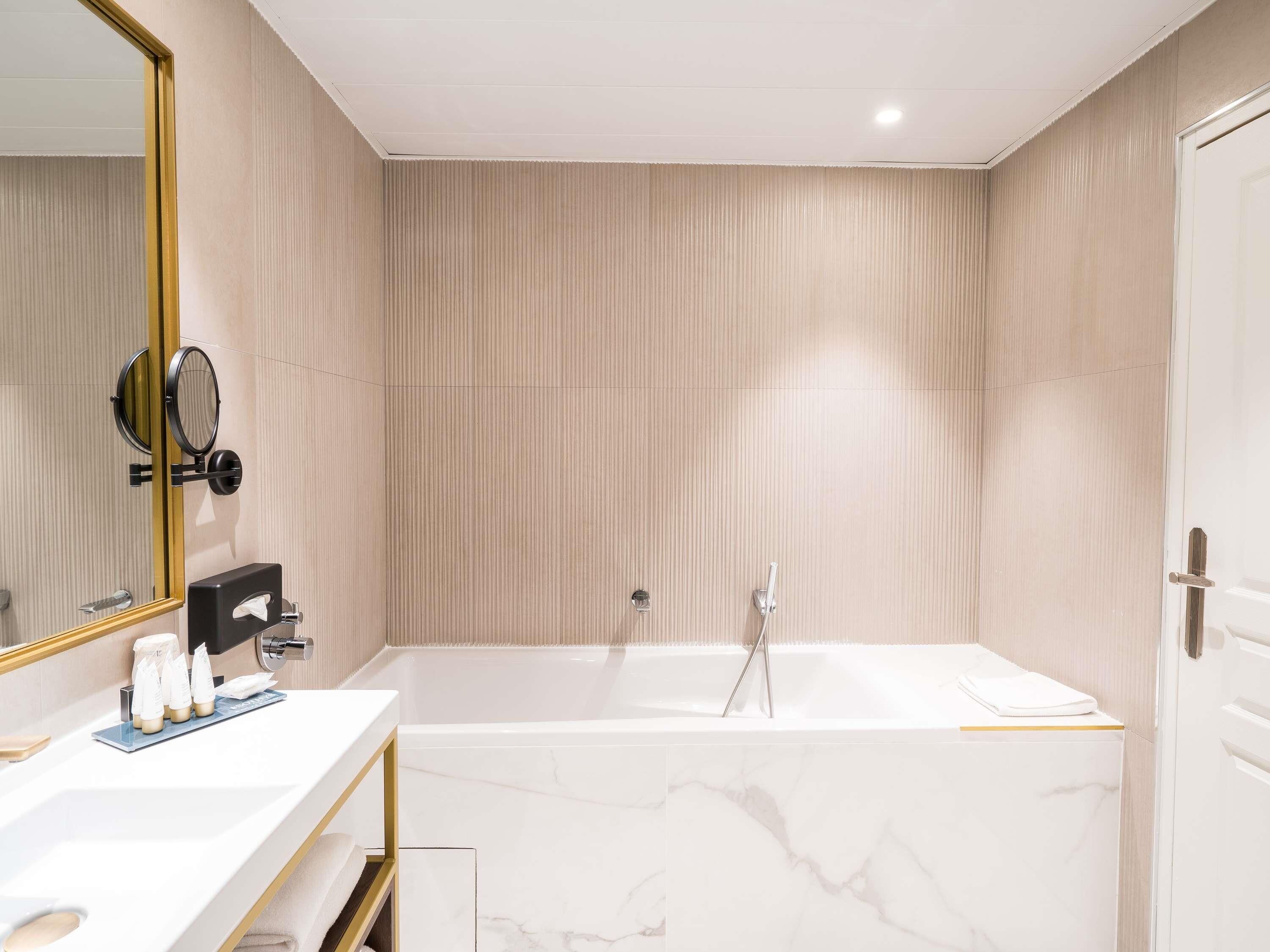A modern bathroom with a large bathtub, a vanity with a mirror, and a towel rack.