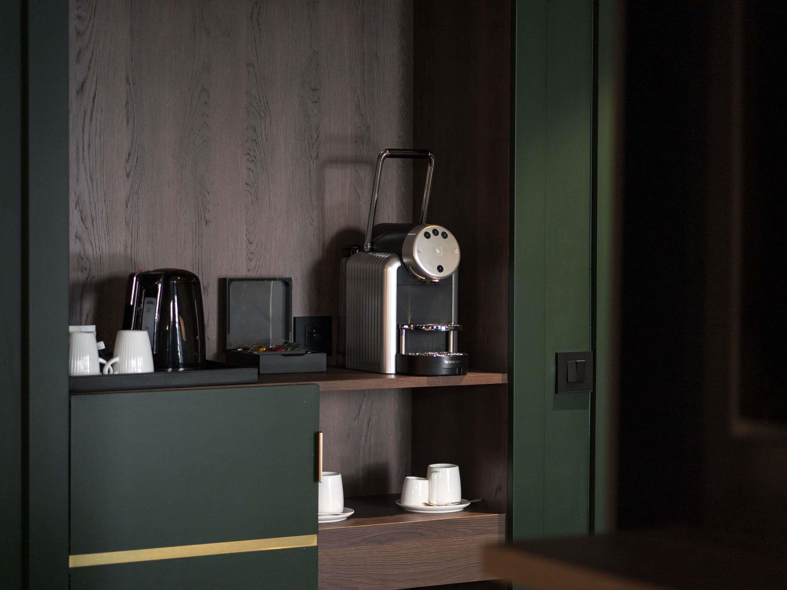 A kitchenette with a coffee maker, a toaster, and a kettle on the countertop.