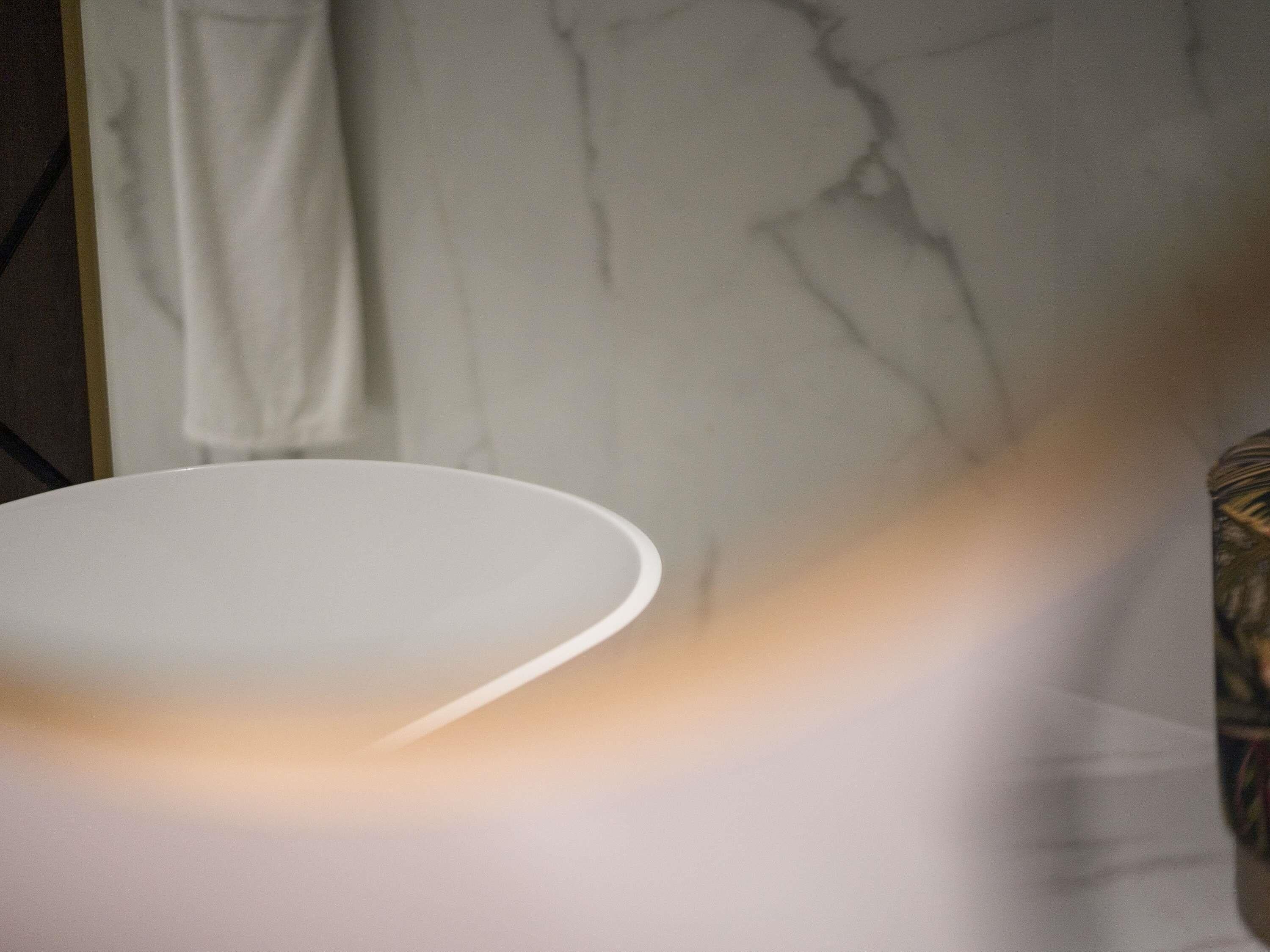 A white table with a curved edge, a marble wall with visible cracks, and a partial view of a patterned fabric.