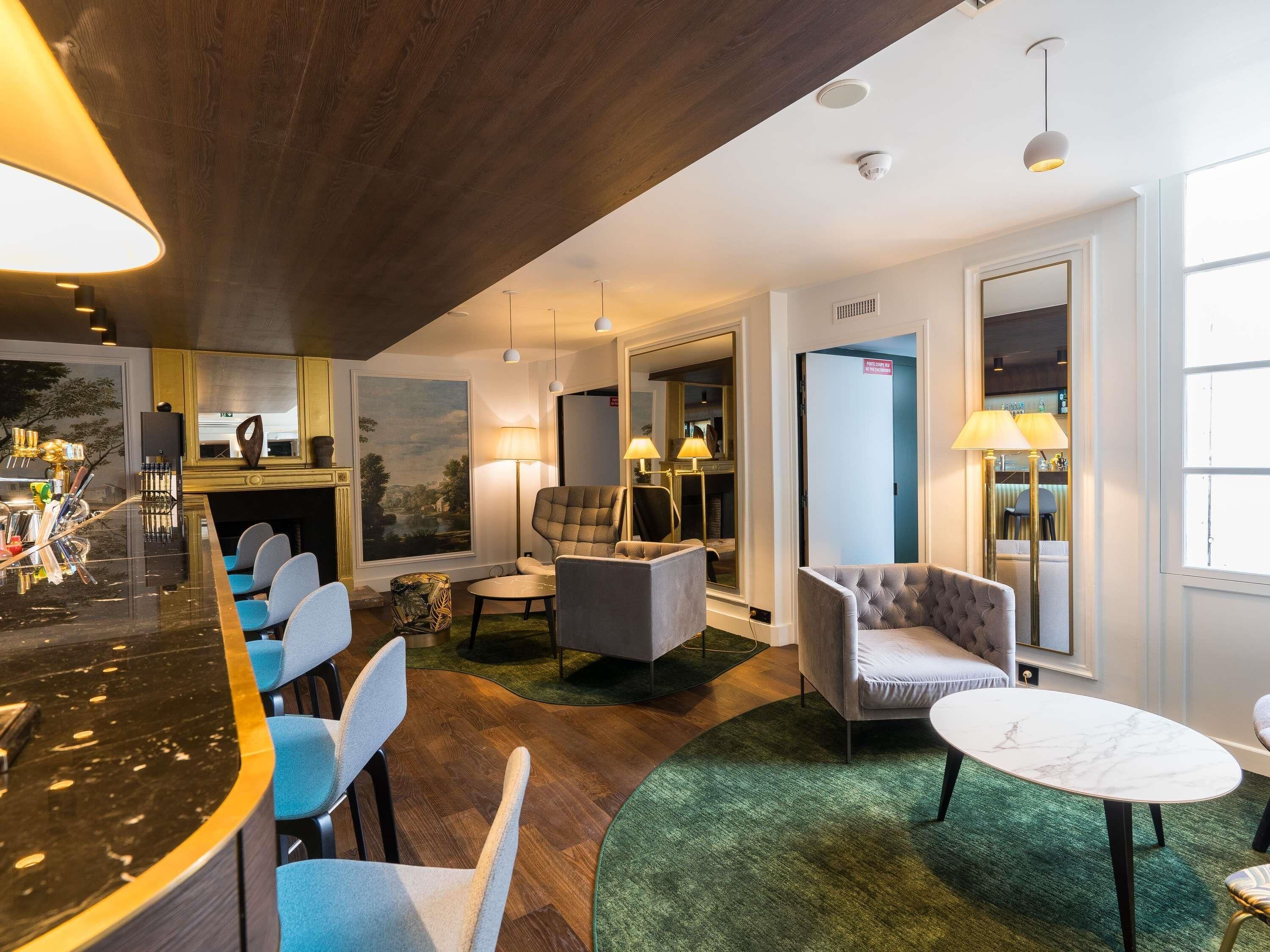 A hotel lobby with a bar, seating area, and a large painting on the wall.