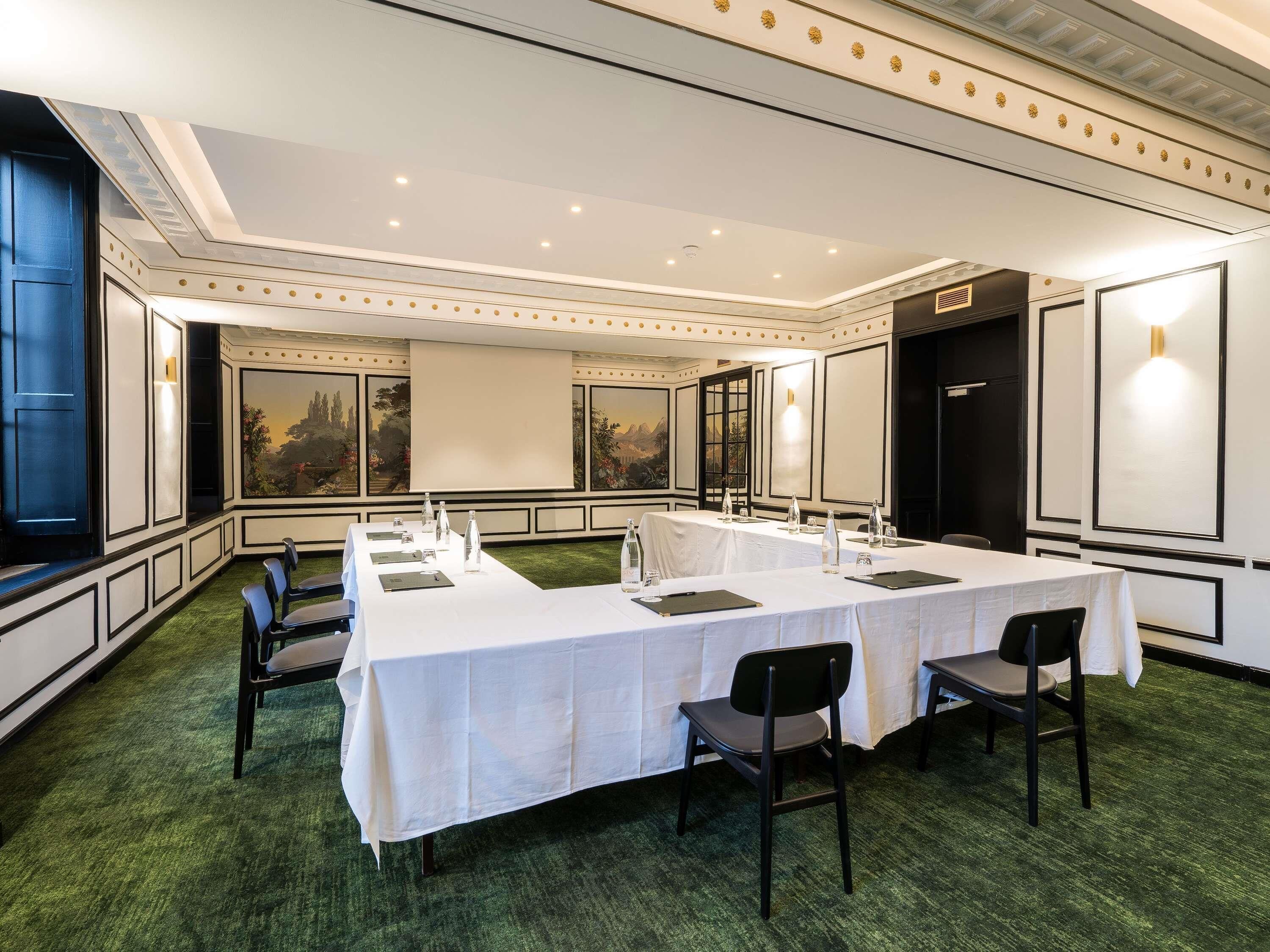 A conference room with a long table, chairs, and a projector screen.