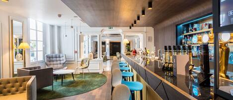 A modern bar area with a long counter, bar stools, and a variety of bottles.