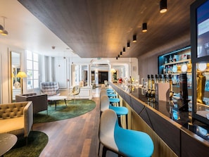 Zona de bar moderna con una barra alargada, taburetes y una variedad de botellas.