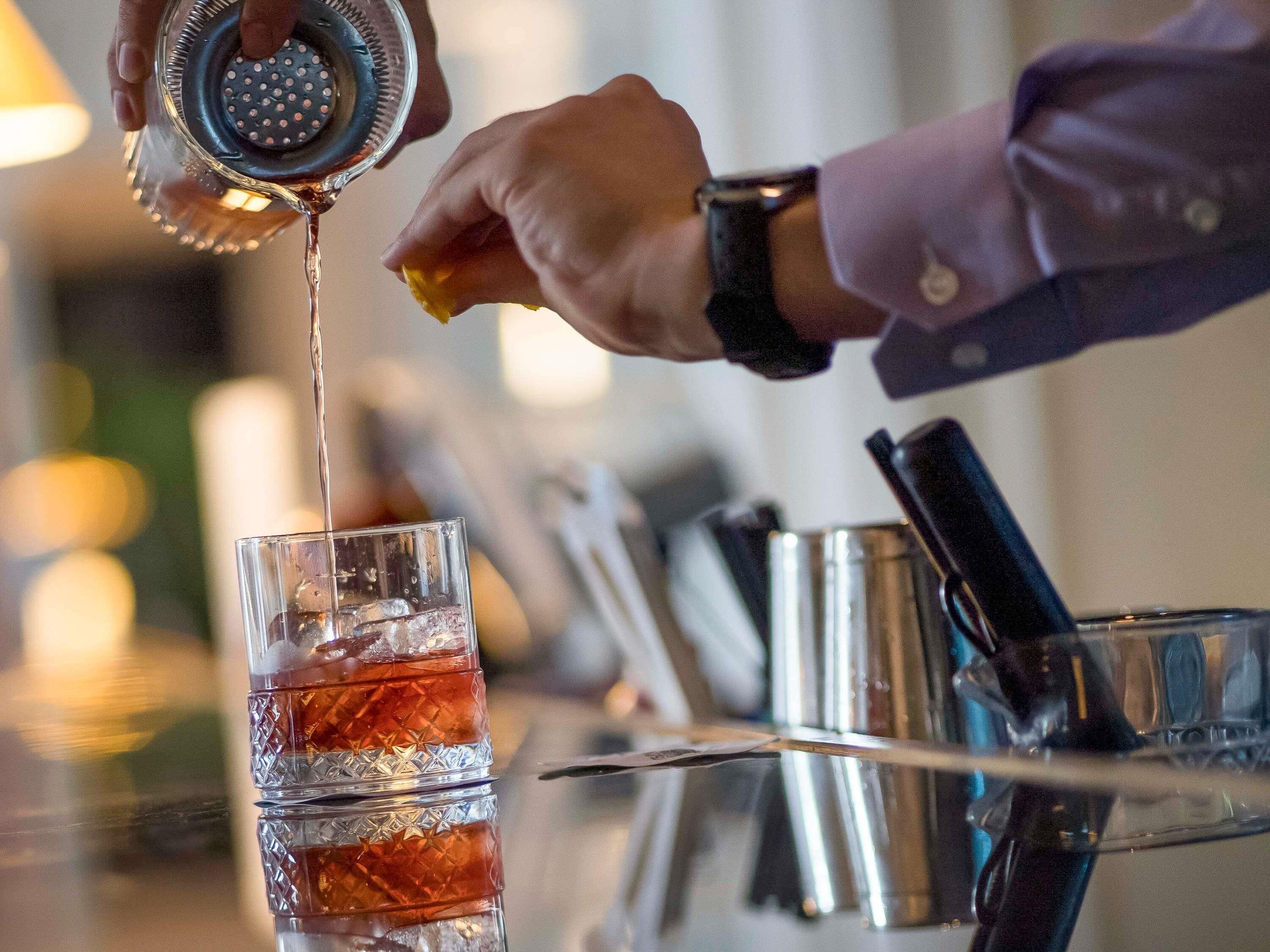 A person squeezing a citrus fruit into a glass.