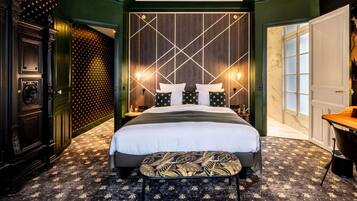 A modern hotel room with a large bed, a desk, and a patterned carpet.