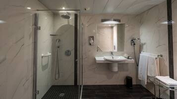 Een moderne badkamer met een douche met glazen wand, een wastafel en een spiegel.