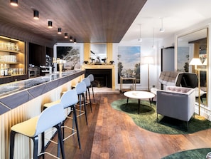 Een moderne bar met krukken, een toog en een open haard.