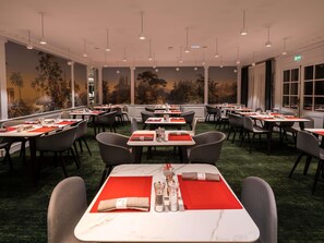 Ein Restaurant mit mehreren Tischen, Stühlen und einem Wandgemälde.