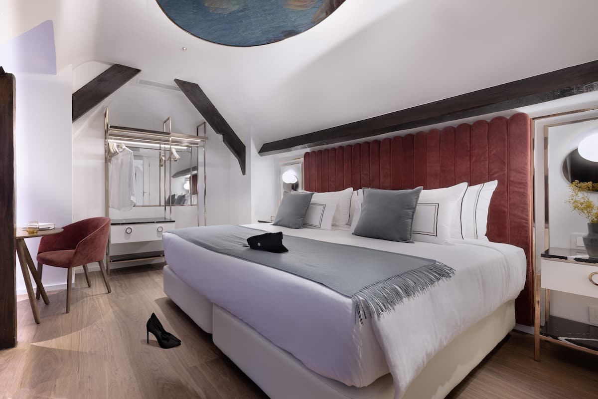 A modern bedroom with a large bed, a desk, and a chair.