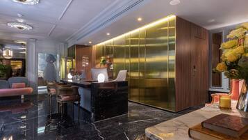 Un moderno vestíbulo de hotel con una recepción, asientos cómodos y un jarrón decorativo con flores.