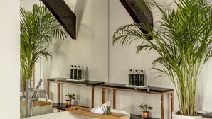 A modern bathroom with a freestanding bathtub, wooden shelves, and potted plants. - Maison Colbert, member of Meliá Collection  Notre-Dame (Paris)