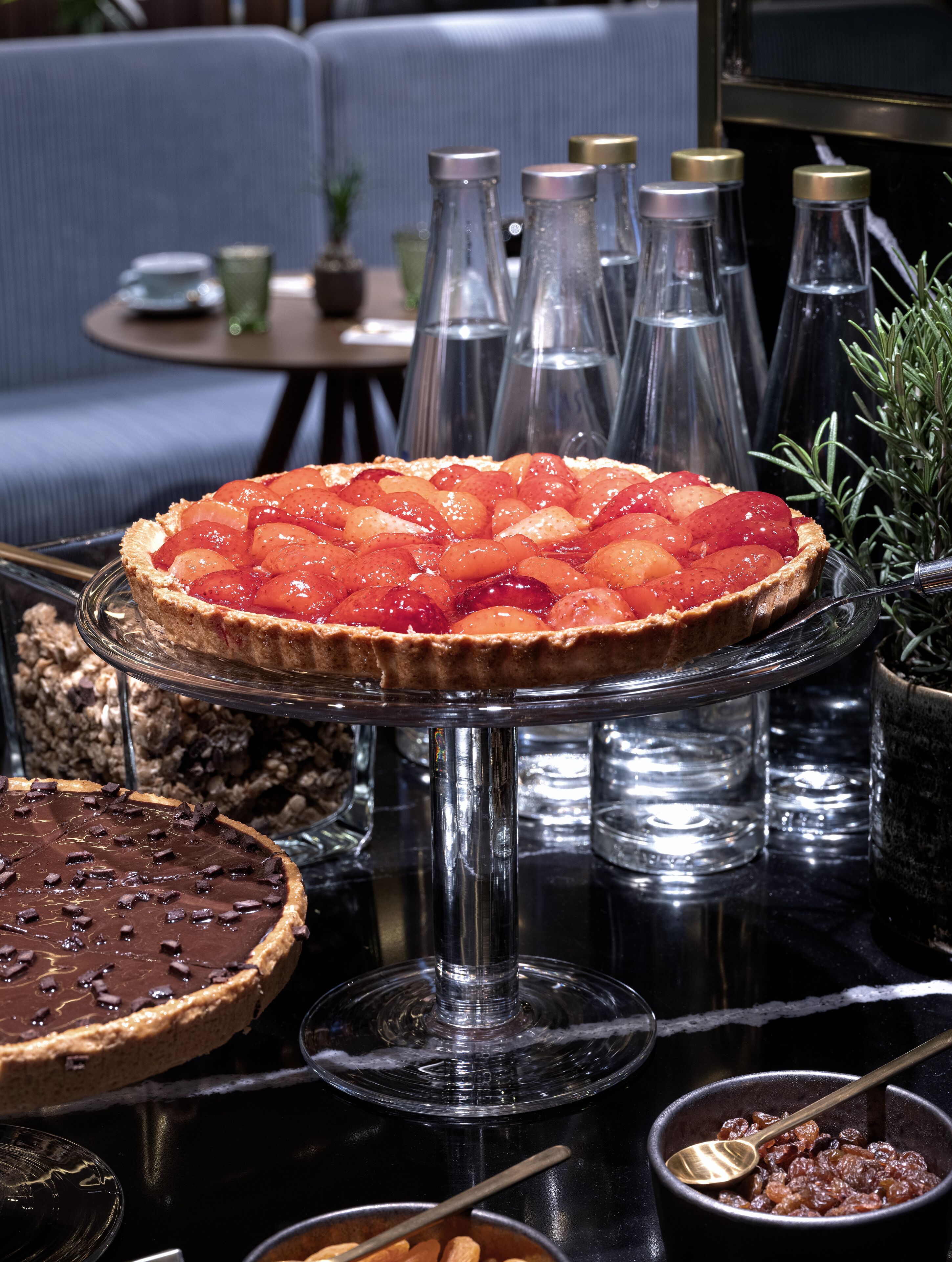A dessert table with various pies and a glass display stand.