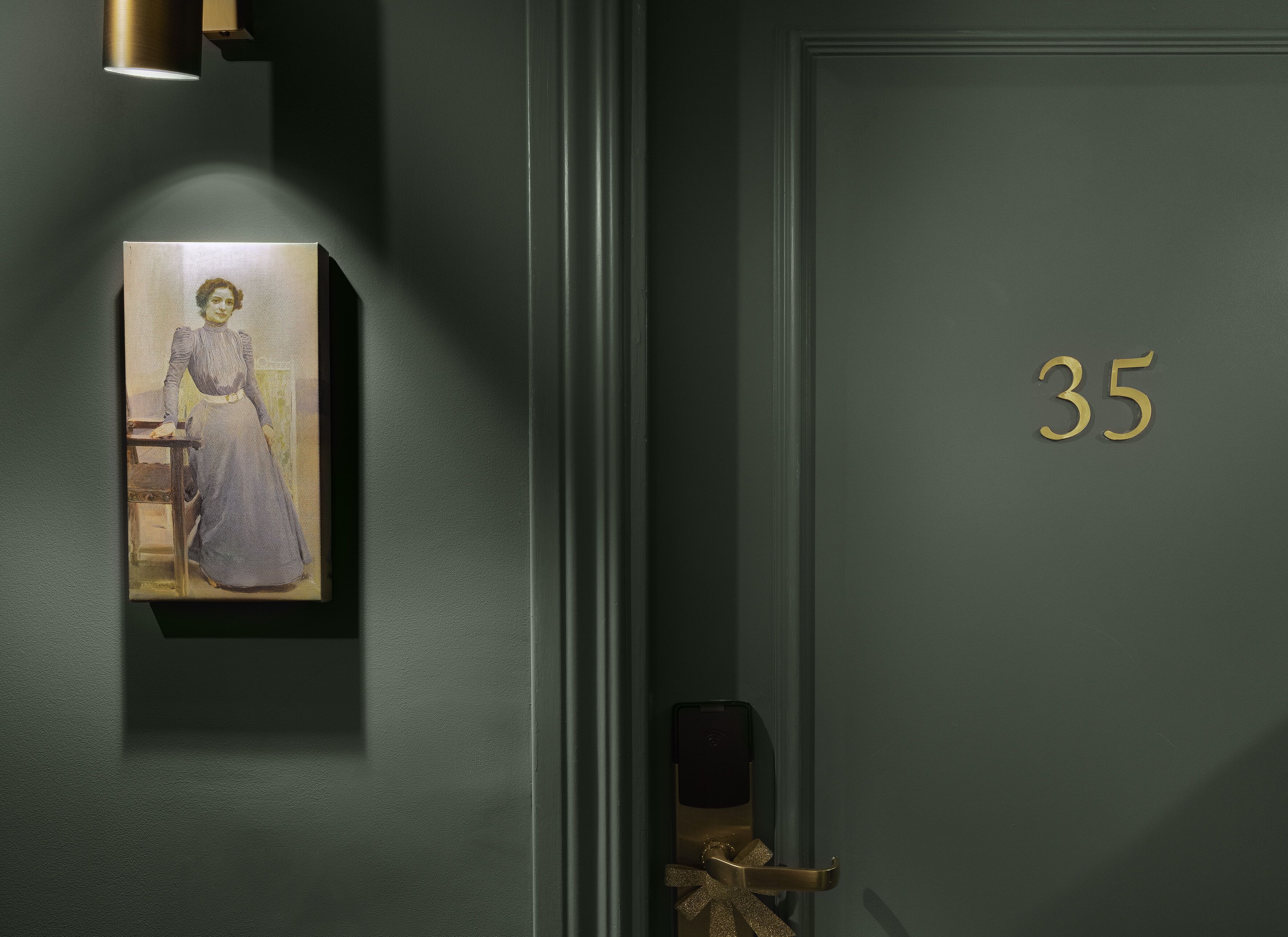 A door with the number 35, a painting of a woman, and a door handle.