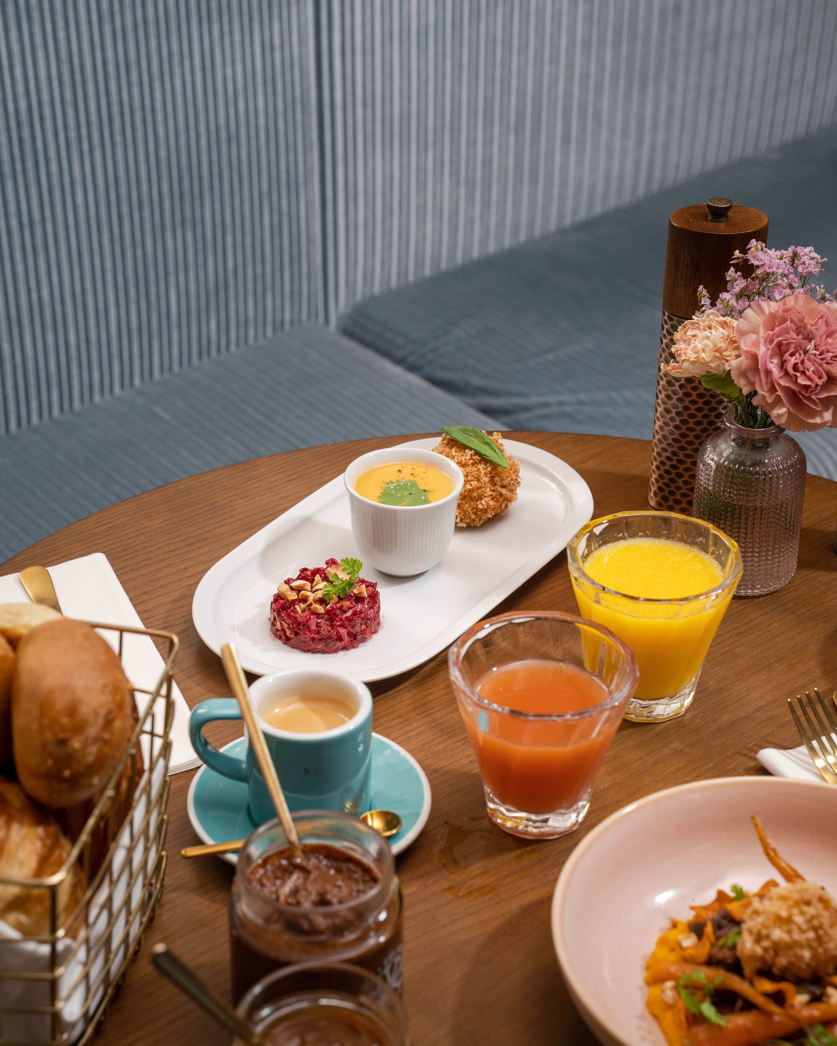 A dining table with a variety of food items, including bread, a small dish of red caviar, a cup of coffee, and a glass of orange juice.