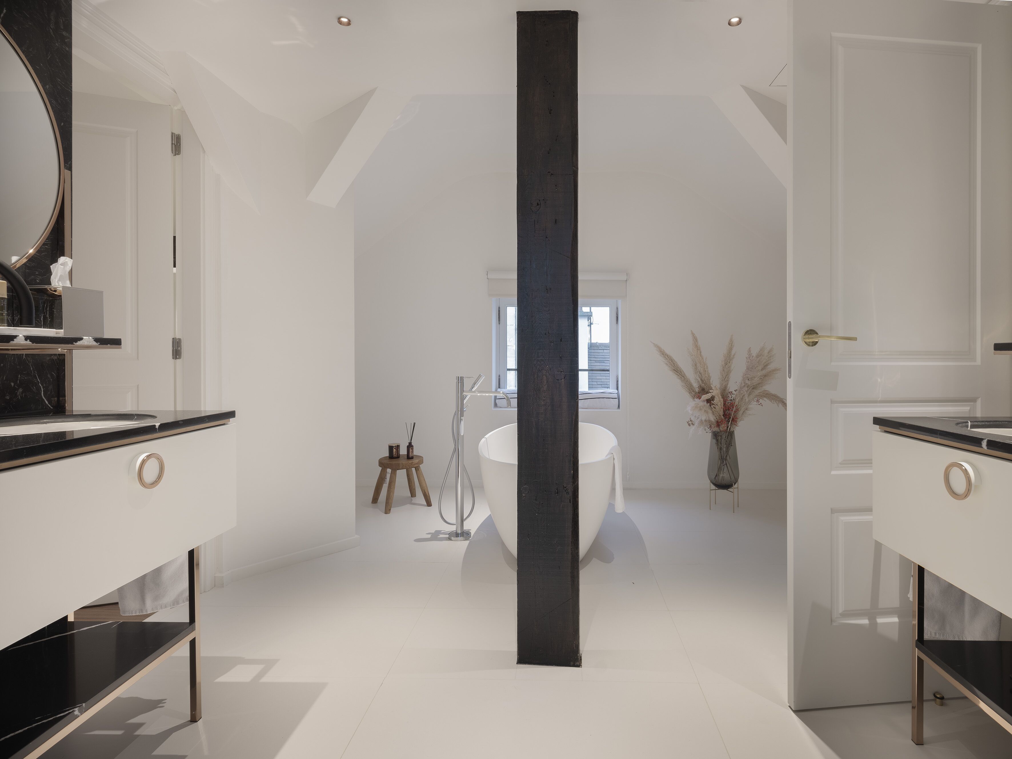 Une salle de bain moderne avec deux vasques, un grand miroir et une colonne centrale.