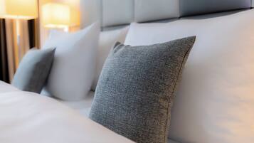 A neatly made bed with white linens and gray pillows.