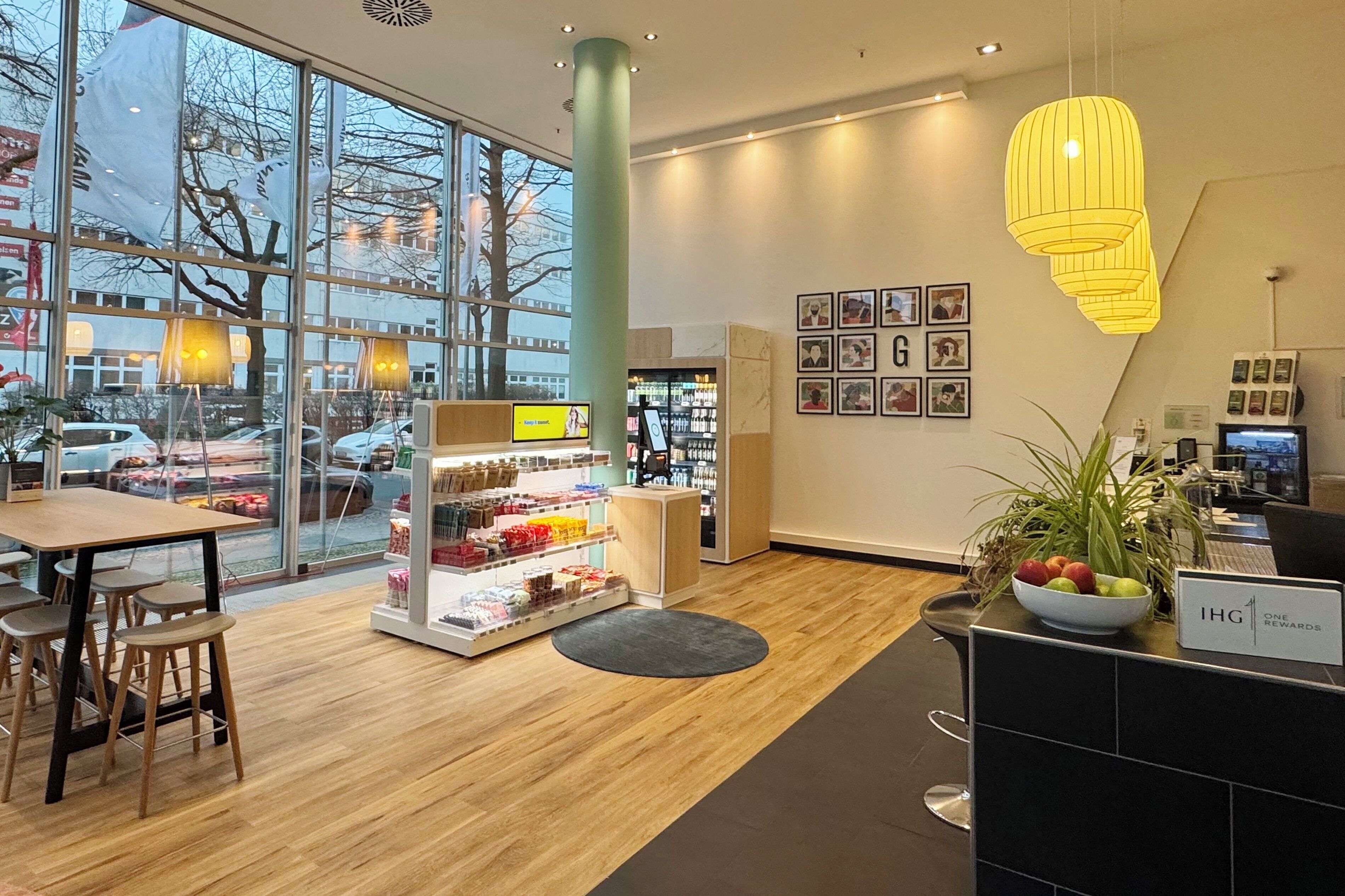 A modern interior with a wooden floor, a reception desk, a fruit bowl, and a display of snacks.