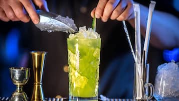 A bartender preparing a cocktail with ice and a lime slice.