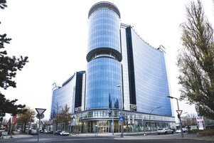 Un hotel moderno con una torre cilindrica e una facciata in vetro.