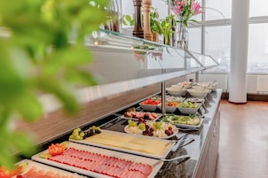 Un buffet con diverse pietanze, tra cui carni, formaggi e frutta.