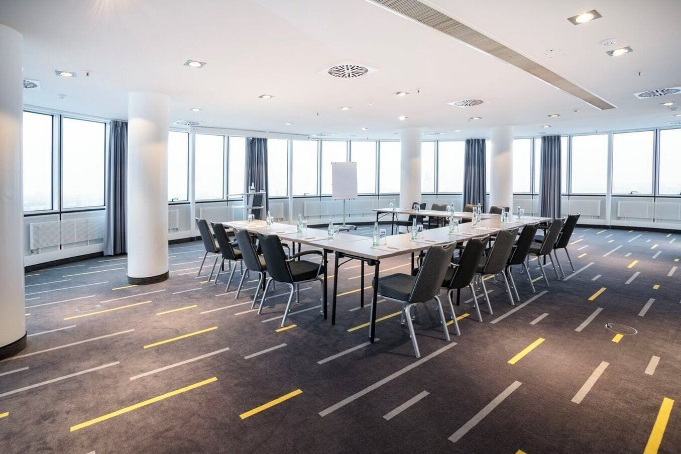 Una sala de conferencias con una larga mesa, sillas y una pantalla para proyector.