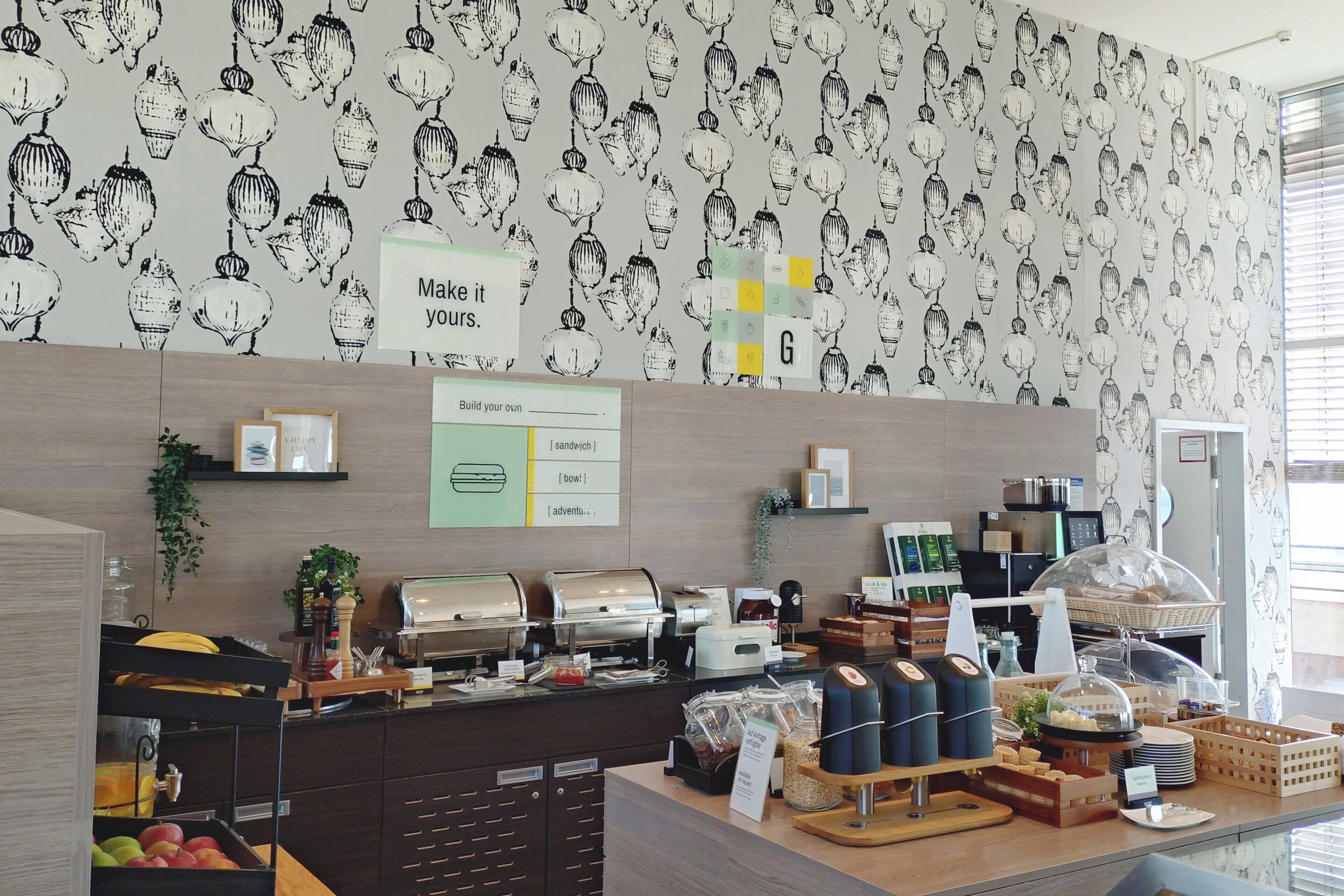 Un café avec une fresque murale, un tableau affichant le menu et divers distributeurs de nourriture et de boissons.