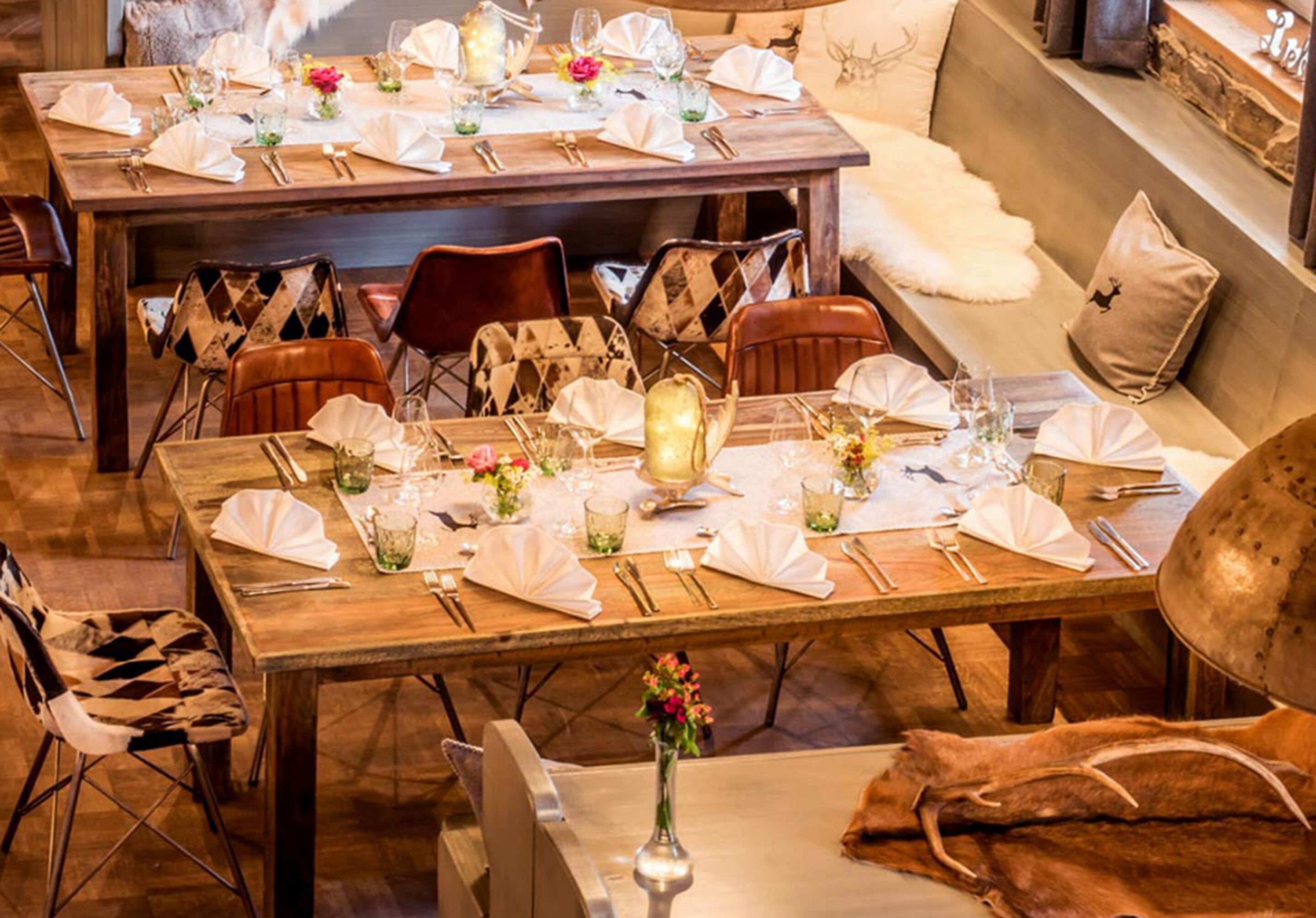 A dining area with wooden tables set for a meal, surrounded by leather chairs.