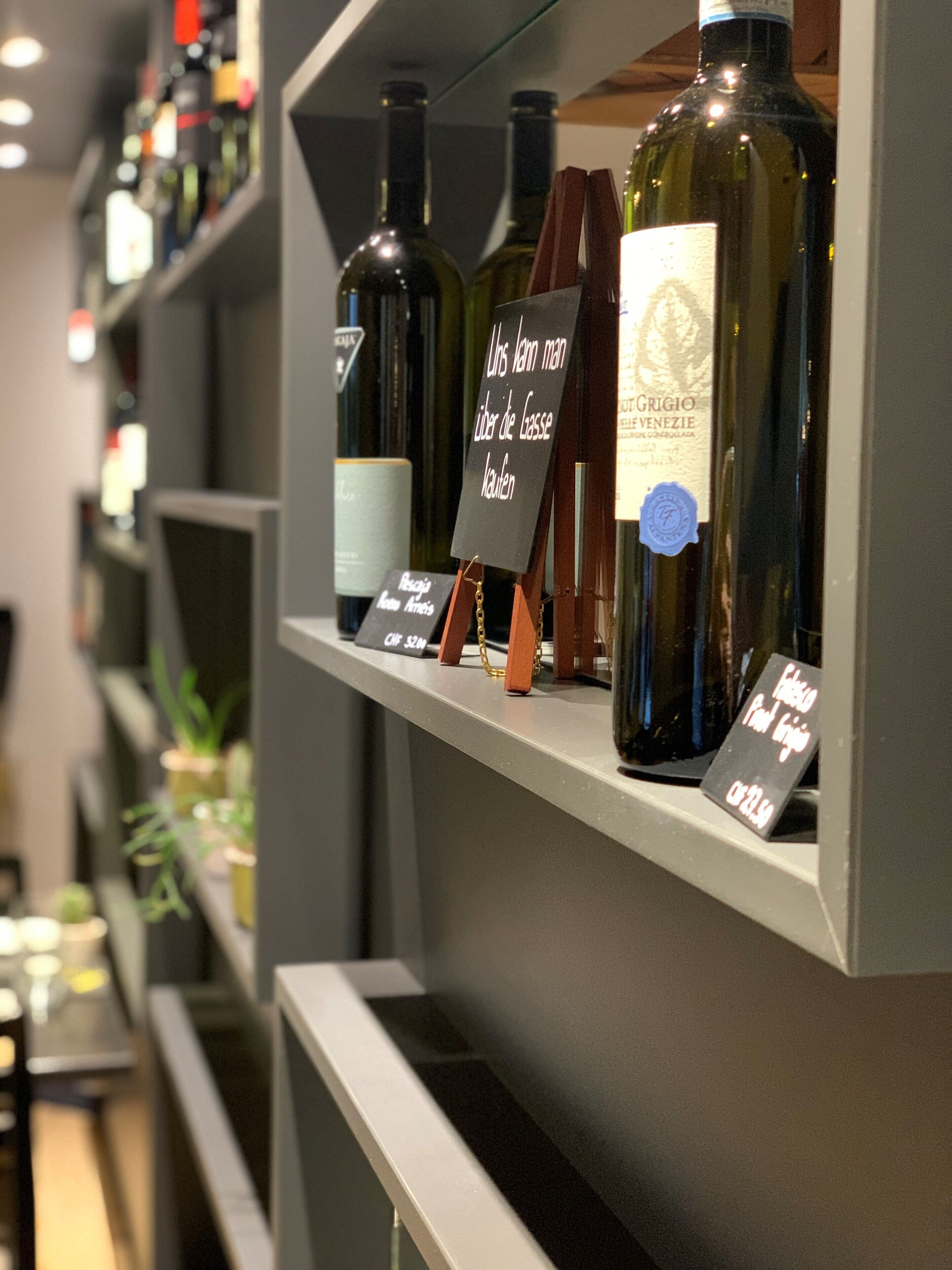A wine rack with various bottles and labels, including a sign with text in a foreign language.
