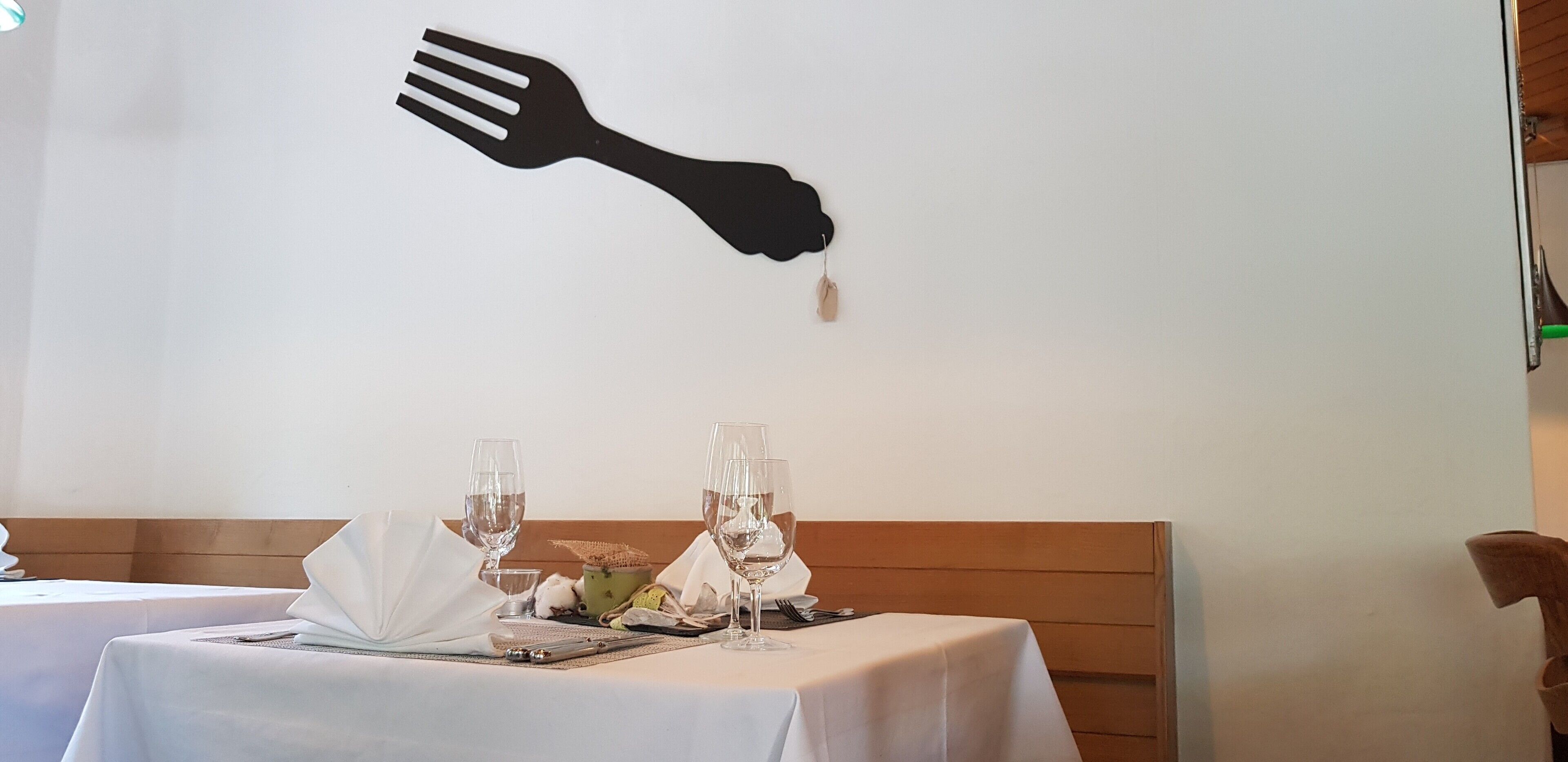 A dining table with two wine glasses, a fork, and a napkin.