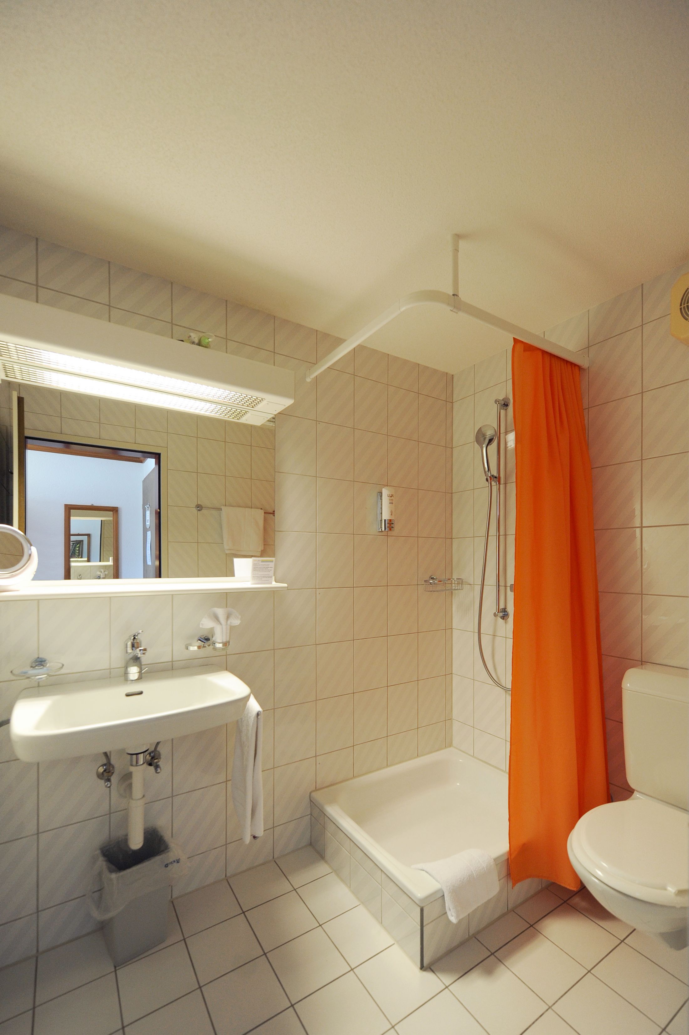 A bathroom with a sink, mirror, shower, and toilet.