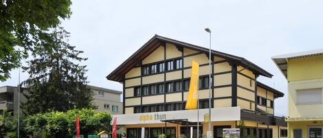 A building with a sign reading "alpha thun" and a yellow flag.